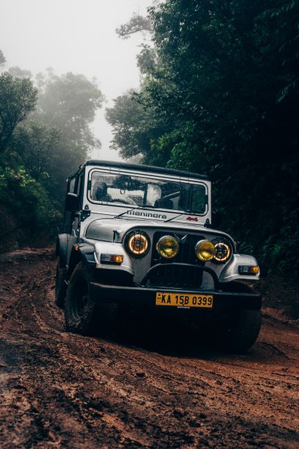 A black off-road vehicle, likely a modern SUV or pickup truck, is shown positioned on uneven, rocky terrain with a rugged and slightly dusty surface. The vehicle features a matte black finish with a p